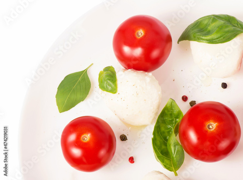 Small tomatoes and cheese. Round camembert cheese with cherry tomatoes and basil on a white plate.