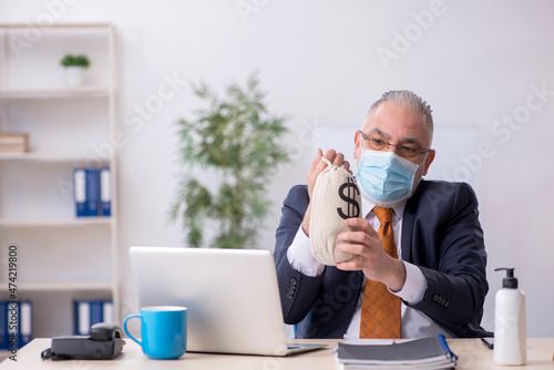 Old male employee during pandemic in remuneration concept