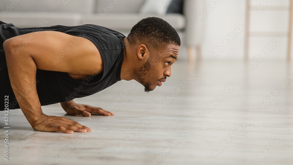 Athletic Black Guy Doing Push-Ups Exercising On Floor At Home