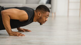 Athletic Black Guy Doing Push-Ups Exercising On Floor At Home
