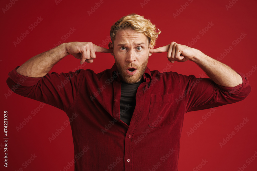 White bearded man expressing surprise while plugging his ears