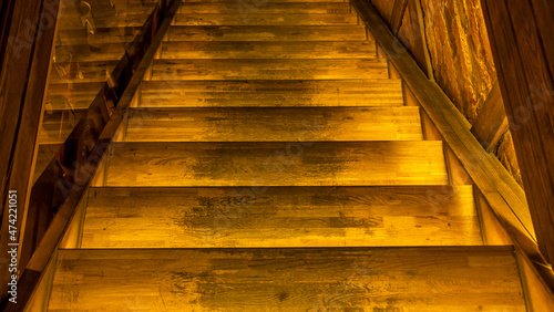 Yellow led light pouring from below onto a wooden staircase. Space for text. Abstract background.