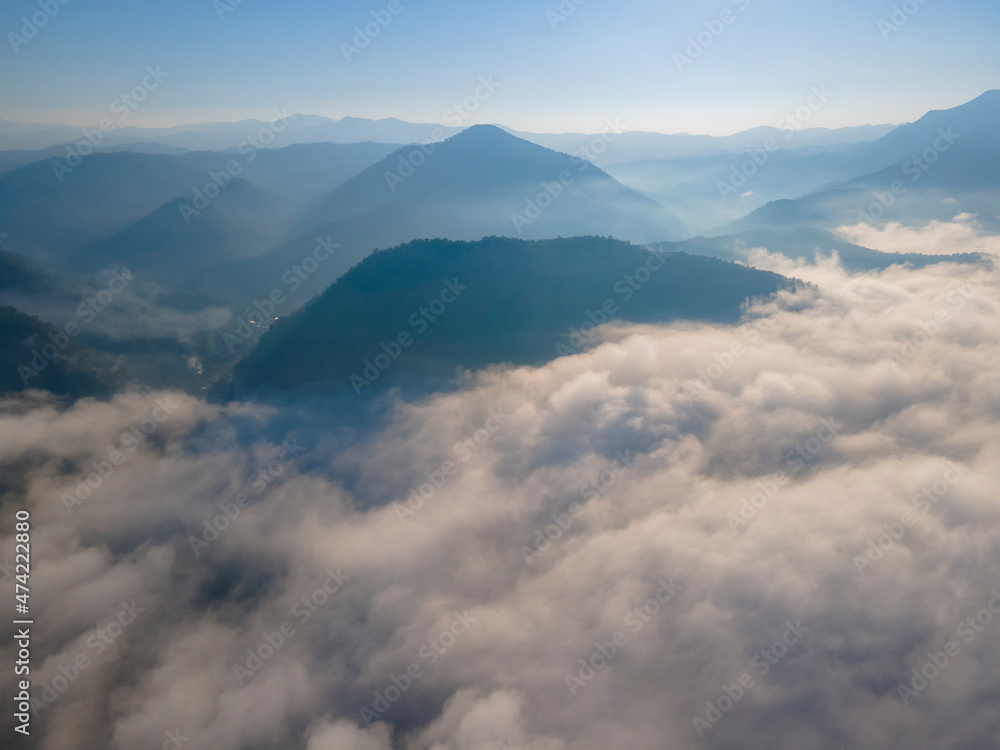 Aerial view over the overlap mountains with a sea of fog during a morning sunrise in the blue sky, Unseen travel in Northern Thailand