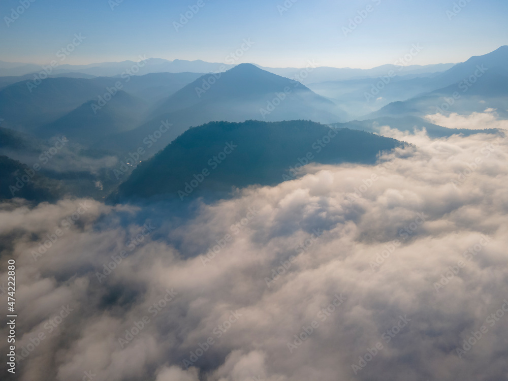 Aerial view over the overlap mountains with a sea of fog during a morning sunrise in the blue sky, Unseen travel in Northern Thailand Aerial view over the overlap mountains with a sea of fog during a morning sunrise in the blue sky, Unseen travel in Northern Thailand