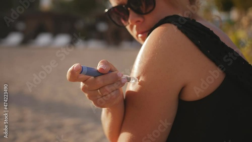 Close-up of a young woman in a swimsuit injecting insulin into her arm with an insulin pen on the seashore. Treatment of diabetes mellitus.