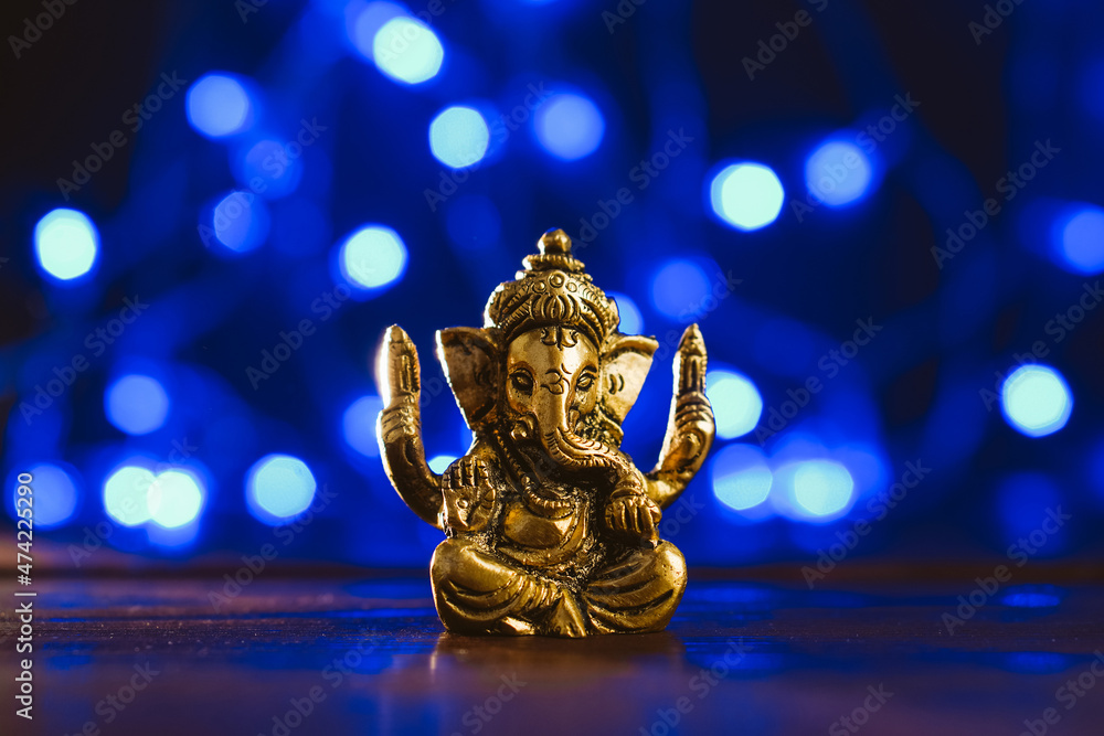 Golden lord ganesha sculpture over blue illuminated background. Celebrate lord ganesha festival