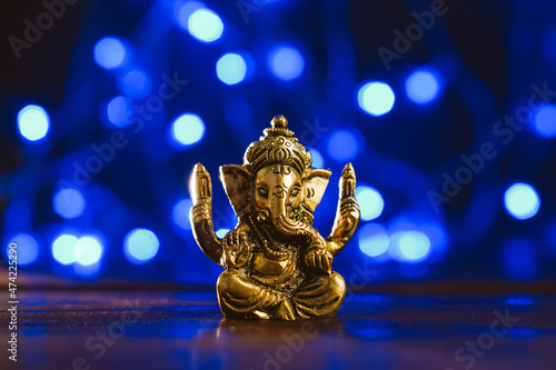 Golden lord ganesha sculpture over blue illuminated background. Celebrate lord ganesha festival