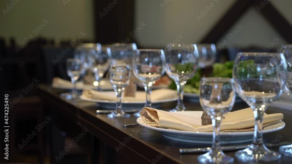 Served table in a restaurant for dinner, lunch or celebration. White plates, beige napkins and glasses, chairs. Holiday indoors. Empty with no people and food. Wooden brown table. Served table in a restaurant for dinner, lunch or celebration. White plates, beige napkins and glasses, chairs. Holiday indoors. Empty with no people and food. Wooden brown table.