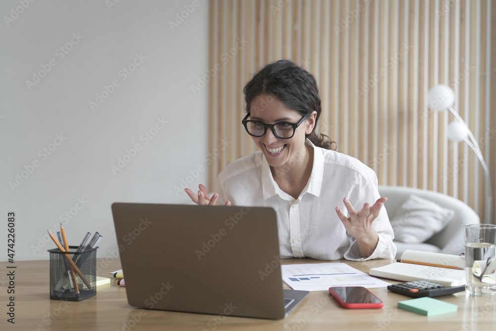 Overjoyed italian businesswoman reading great news on laptop at her workplace Overjoyed italian businesswoman reading great news on laptop at her workplace