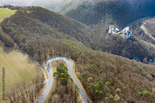 Bird's eye view of a very winding road through the forest in Taunus / Germany with the Arnstein monastery in the background photo