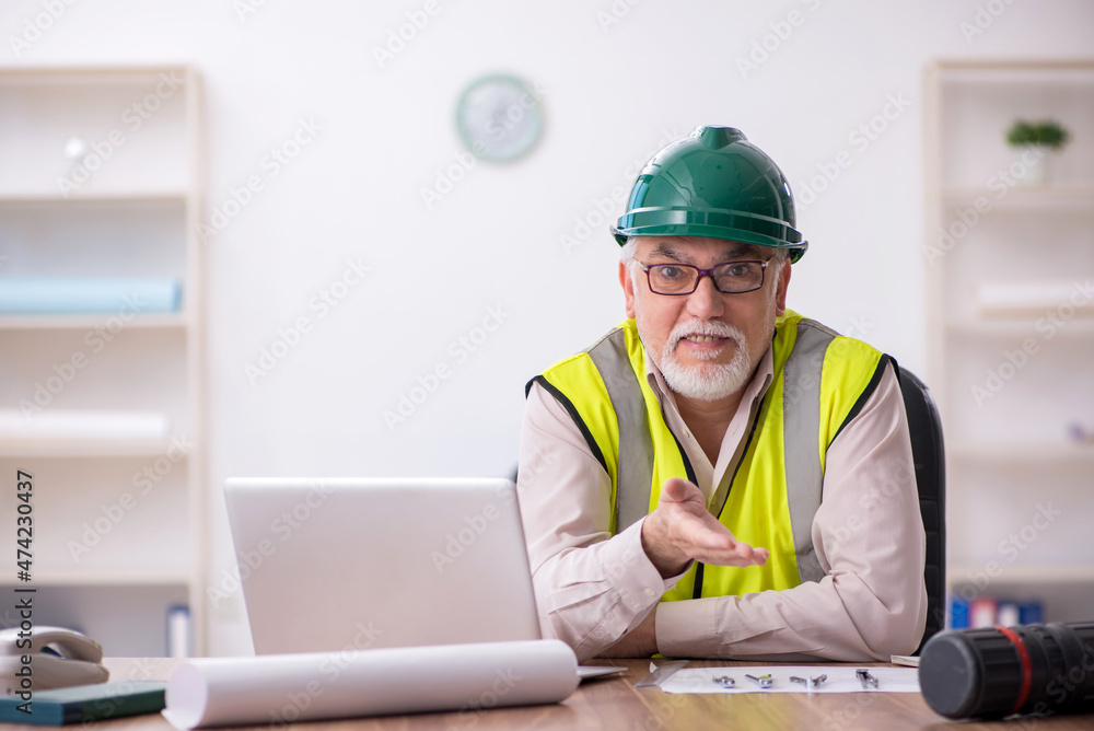 Old male architect working in the office Old male architect working in the office