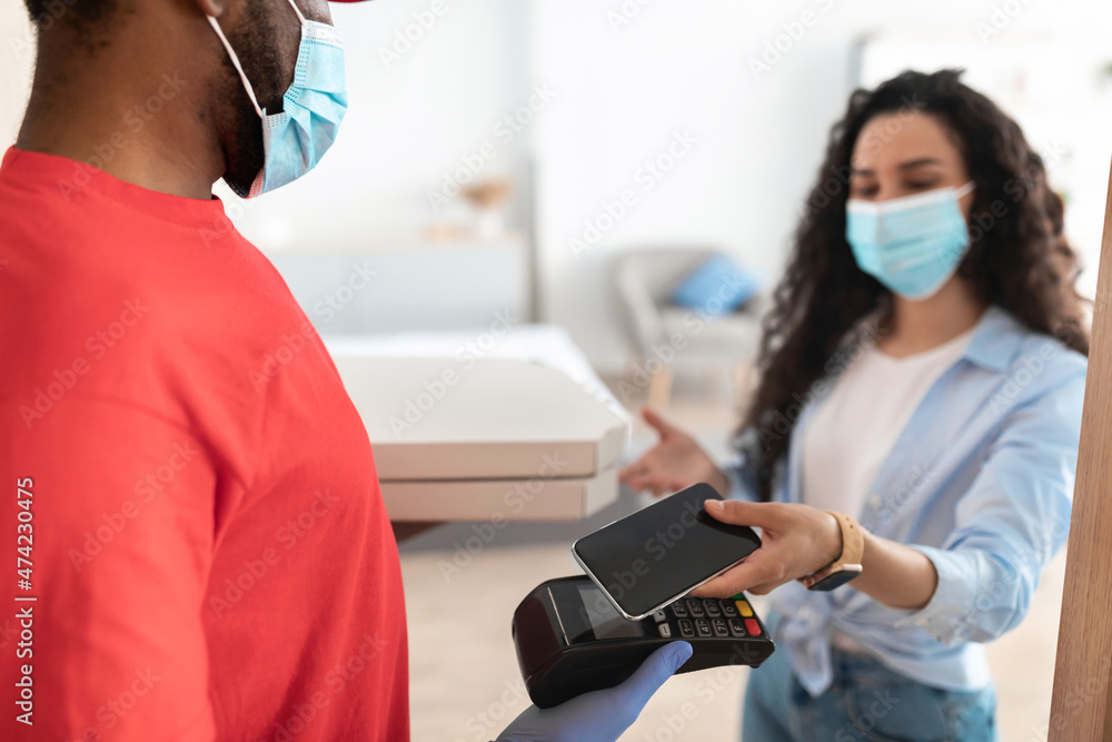 Black man holding POS machine client paying with smartphone Black man holding POS machine client paying with smartphone