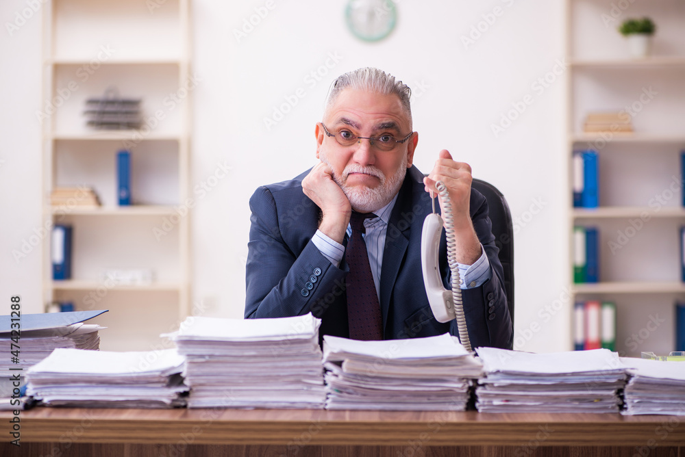 Old businessman employee unhappy with excessive work in the office Old businessman employee unhappy with excessive work in the office