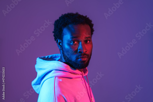Young black man in hoodie posing and looking at camera