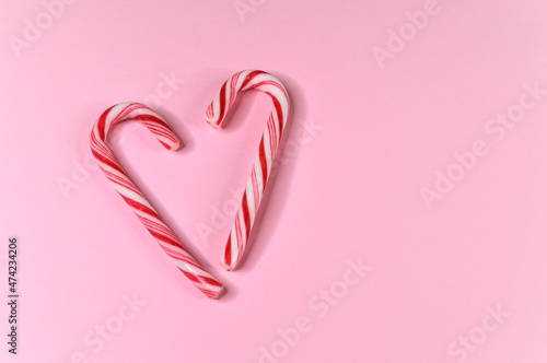 pair of candy canes in shape of heart on pink background