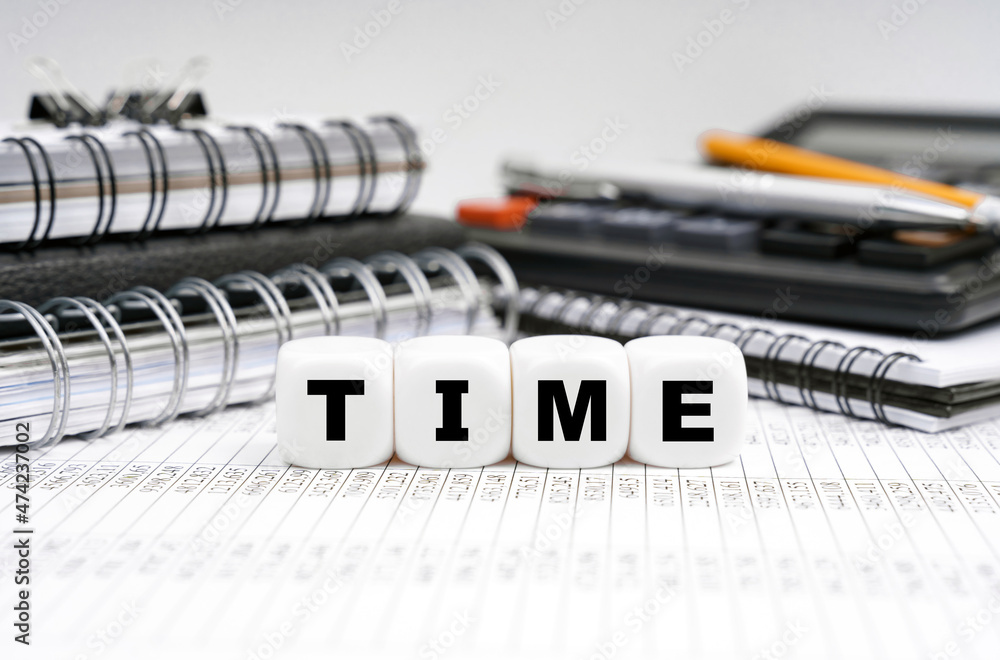 On the table, among office objects, cubes with the inscription - TIME On the table, among office objects, cubes with the inscription - TIME