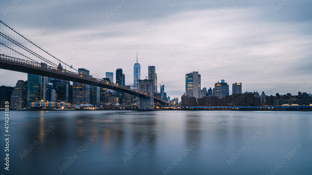 Fototapeta premium Panoramic, calm view of Brooklyn bridge and lower Manhattan, New York City at twilight