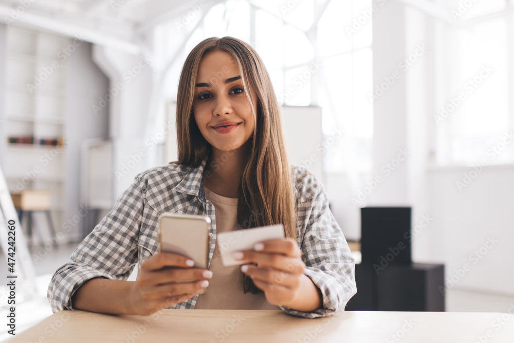 Girl looking on business card and mobile phone Girl looking on business card and mobile phone