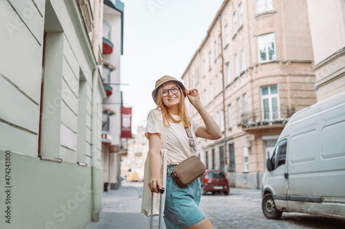 Portrait happy woman traveler tourist walking with luggage outdoors in urban city. Active and tourist lifestyle concept