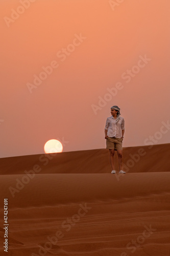 Photo of a woman in a desert at sunset with the sun in the background
