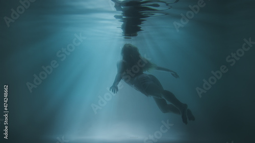 A girl floats to the surface under water against a background of sunshine © davstudio