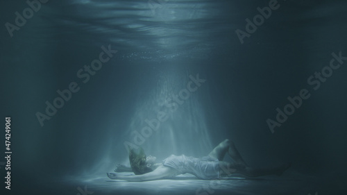 a girl in a white dress falls under the water