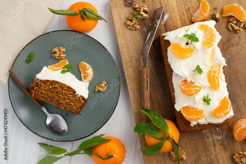 Obraz na plátne Vegan tangerine sponge cake with a giant frosting and mandarin orange wedges on a wooden board