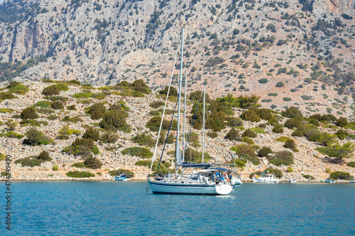 White boat sailing close to the coast blue aegean sea in Greece photo