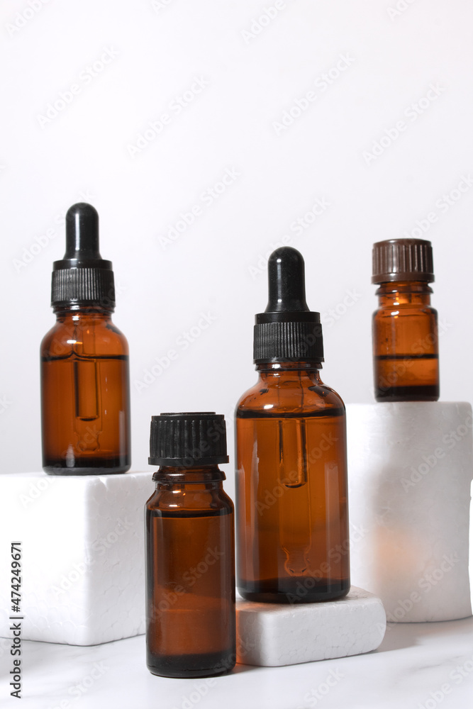 A mock-up of an empty glass dropper bottle made of brown glass stands on a white podium and a white background. Skin care serum, banner or template. The concept of a natural cosmetic product.Copyspace A mock-up of an empty glass dropper bottle made of brown glass stands on a white podium and a white background. Skin care serum, banner or template. The concept of a natural cosmetic product.Copyspace