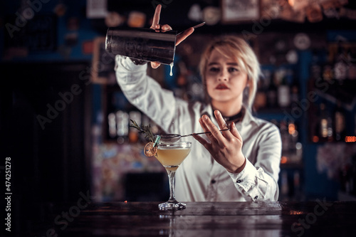 Girl barman mixes a cocktail on the beerhouse