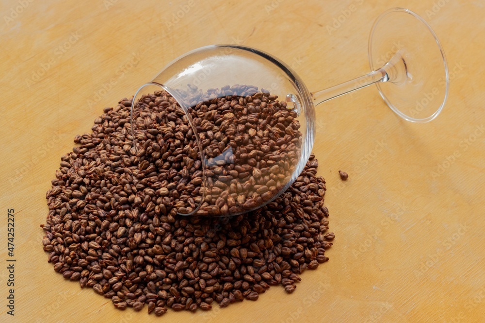 Lying wine glass with a scattering of grape seeds on a wooden texture background