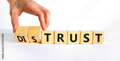 Distrust or trust symbol. Businessman turns wooden cubes, changes words 'distrust' to 'trust'. Beautiful white table, white background. Business and distrust or trust concept, copy space. photo