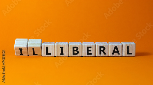 Illiberal or liberal symbol. Turned wooden cubes and changed the word illiberal to liberal. Beautiful orange background. Business, political and illiberal or liberal concept. Copy space. photo