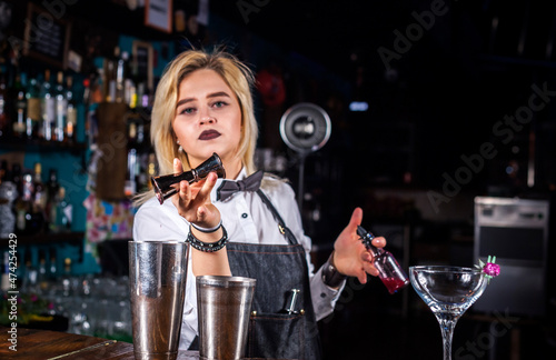 Experienced woman bartending pouring fresh alcoholic drink into the glasses at the night club