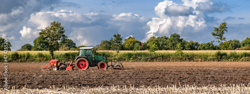 Obraz na plátně Rural panorama with cumulus clouds in the sky and a tractor in the field cultiva