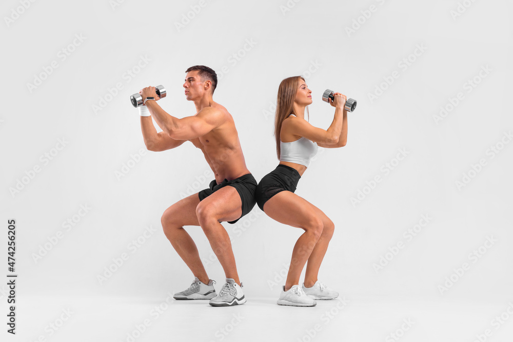 Fit couple at the gym isolated on white background with dumbbells. Fitness concept. Healthy life style. Fit couple at the gym isolated on white background with dumbbells. Fitness concept. Healthy life style.