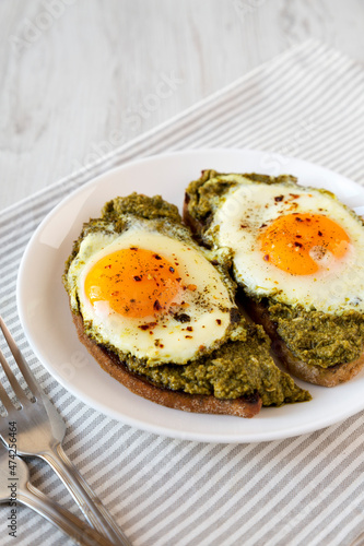 Homemade Pesto Egg Toast on a white plate, side view.