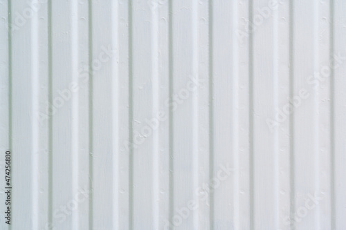 The ribbed surface of the metal radiator of the heating system is white. Brush marks are visible. Close-up. Background. Texture.