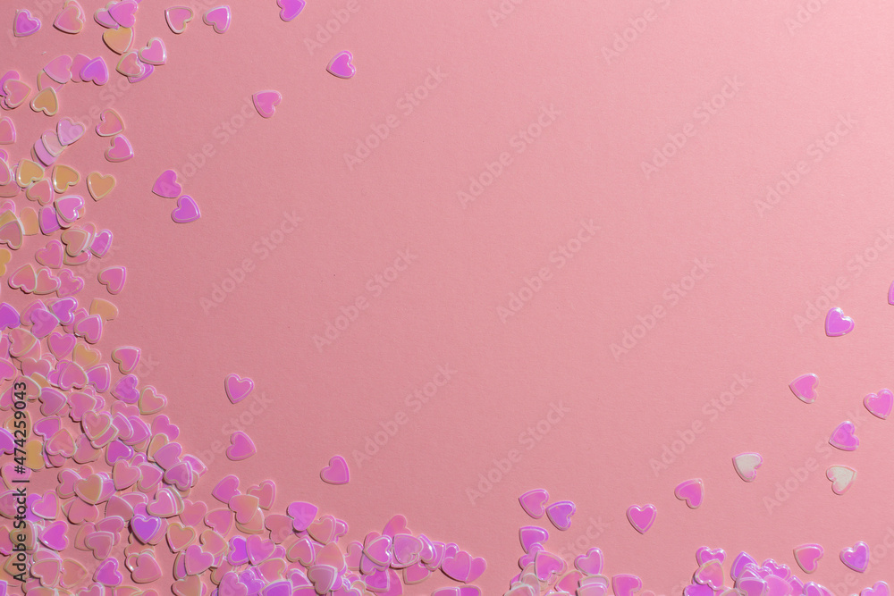 sequins-confetti in the shape of hearts on a pink background. valentine's day concept
