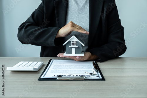 Real estate agent covering Small house model and protection by hands