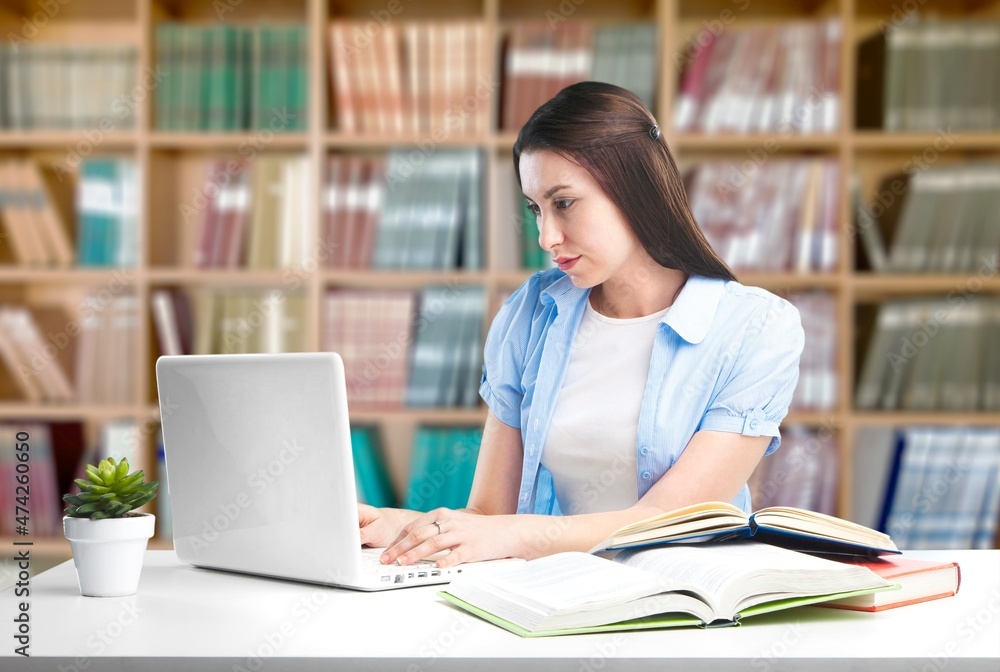 A female professor used laptop while doing a research at university library. A female professor used laptop while doing a research at university library.