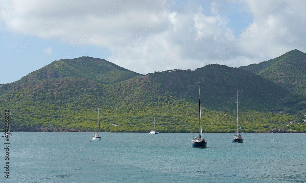 Small boats in the harbor, green hills in the background. Antigua 