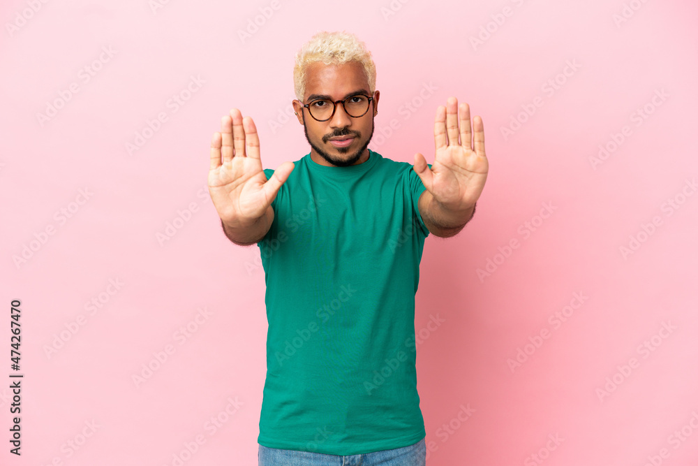 Young Colombian handsome man isolated on pink background making stop gesture and disappointed Young Colombian handsome man isolated on pink background making stop gesture and disappointed