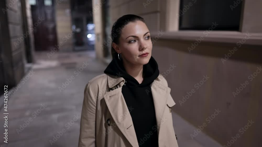 Young woman walking in empty street at night. Pretty lady in trench coat goes to meeting. Urban lifestyle. Young woman walking in empty street at night. Pretty lady in trench coat goes to meeting. Urban lifestyle.