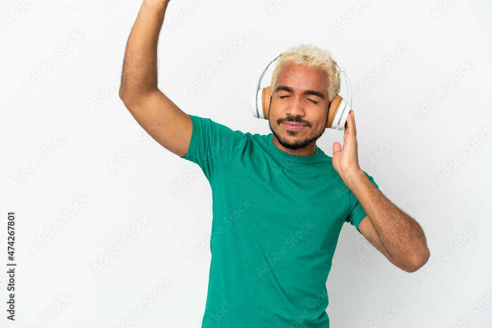 Naklejka premium Young Colombian handsome man isolated on white background listening music and dancing