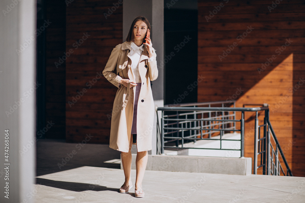 Young beautiful woman wearing coat walking in the city and talking on the phone