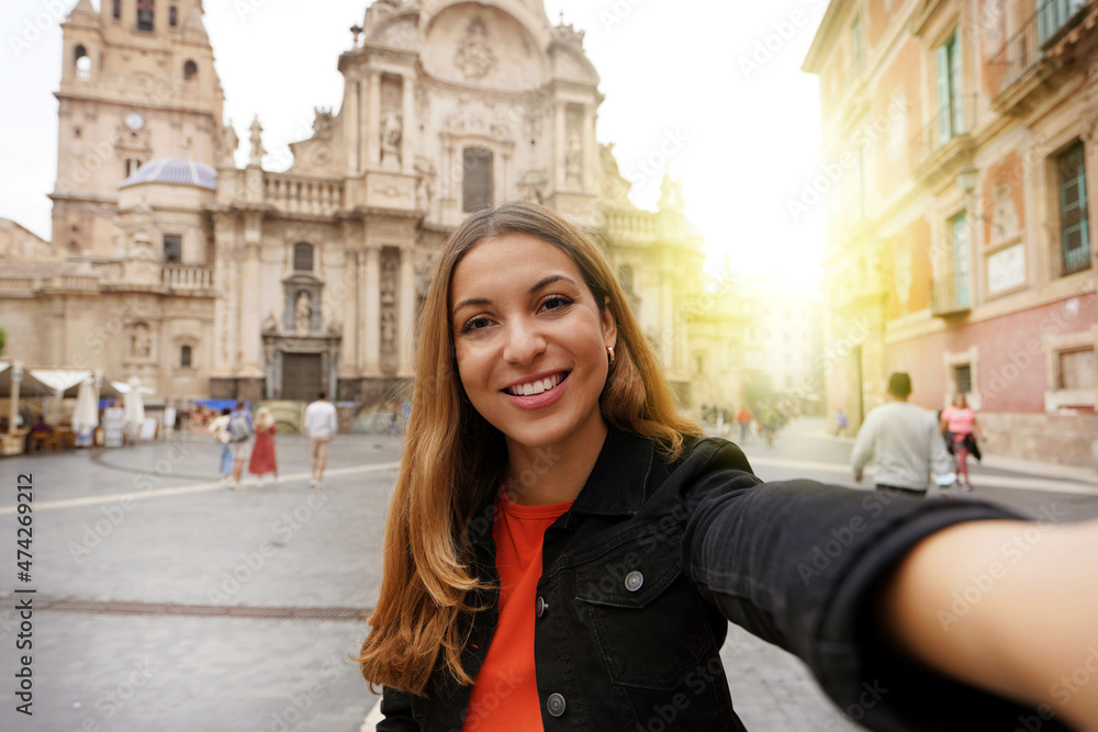 Tourist girl in Murcia taking selfie photo with the Cathedral Church of Saint Mary and cityscape on the background. Girl takes self portrait in Murcia, Spain. Tourist girl in Murcia taking selfie photo with the Cathedral Church of Saint Mary and cityscape on the background. Girl takes self portrait in Murcia, Spain.