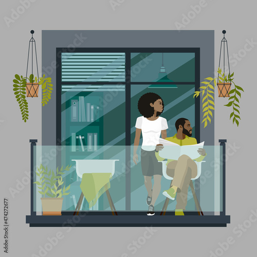 An African-American couple is on the balcony against the backdrop of a large glass doorway. Modern glass balcony with green plants in pots.