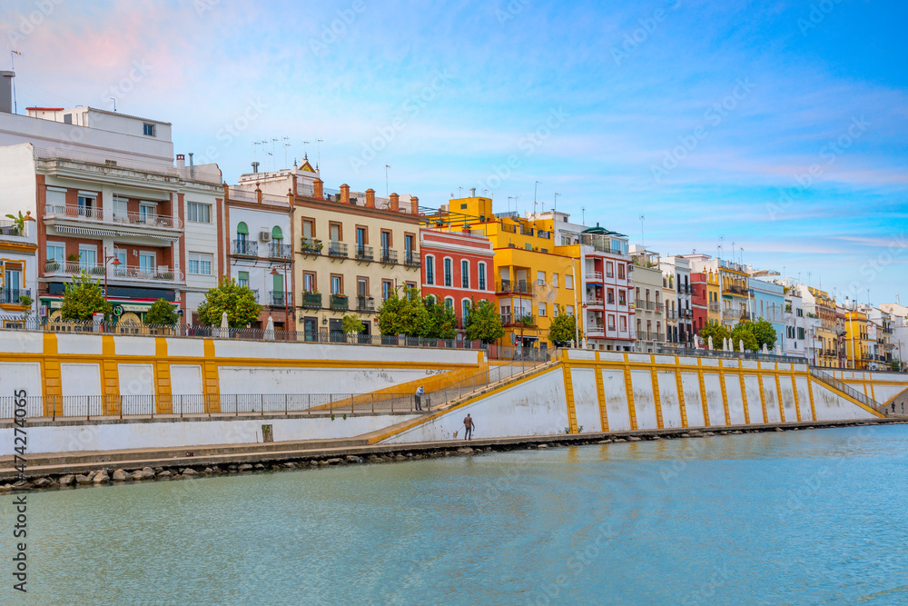 Fototapeta premium Colorful buildings including homes and shops face the Guadalquivir River in the Triana District of the Analusian city of Seville, Spain.