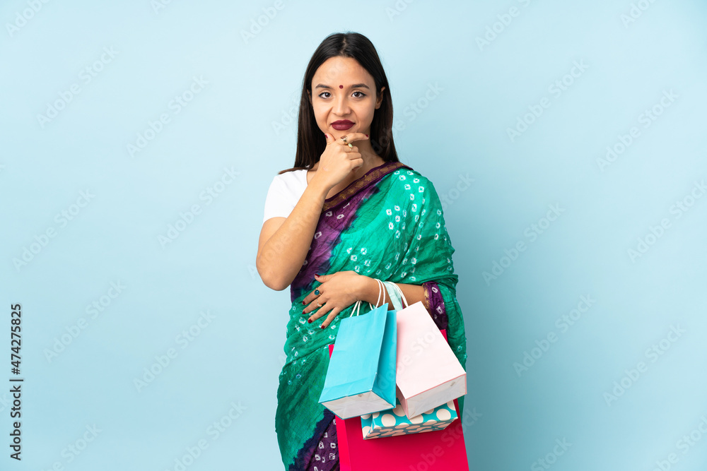 Young Indian woman with shopping bags thinking